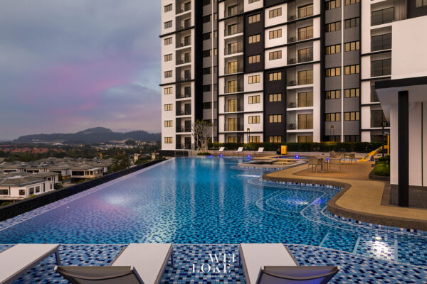 Outdoor rooftop pool beside a modern high-rise residential building at dusk, with lounge chairs and distant hills in a pastel sky